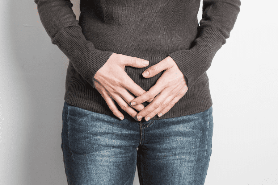 Woman holds stomach due to bladder discomfort