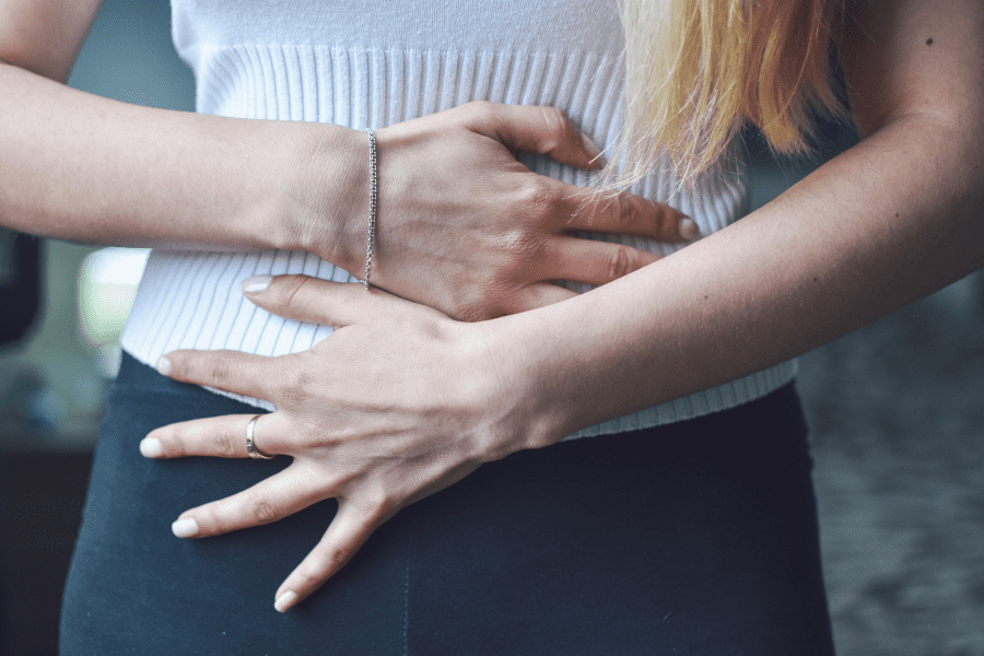 A woman holds her stomach with both hands