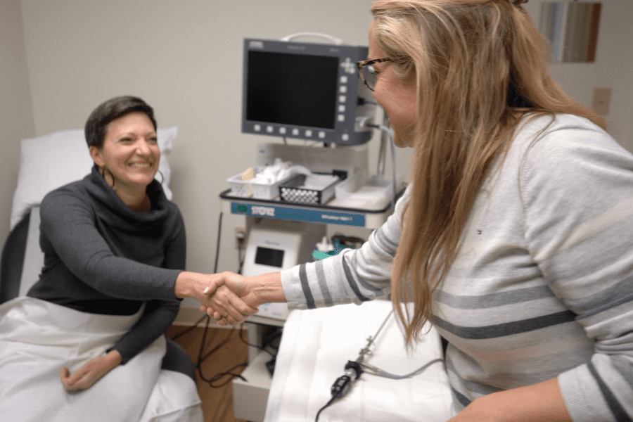 Female doctor shaking hands with female patient in in medical office